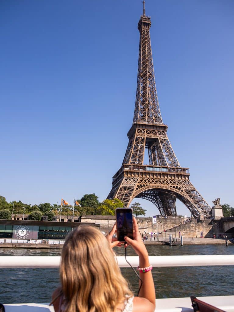 young girl taking photo of eiffel tower