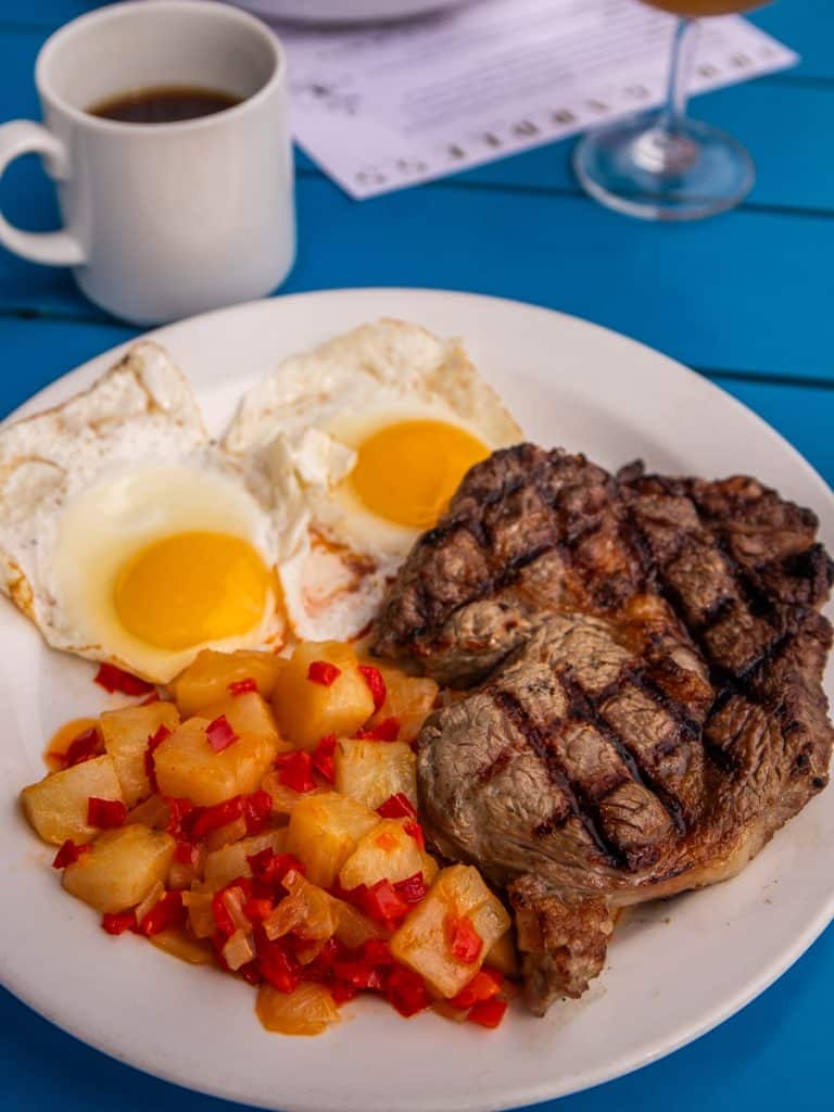 Steak and eggs, breakfast potatoes, black coffee.