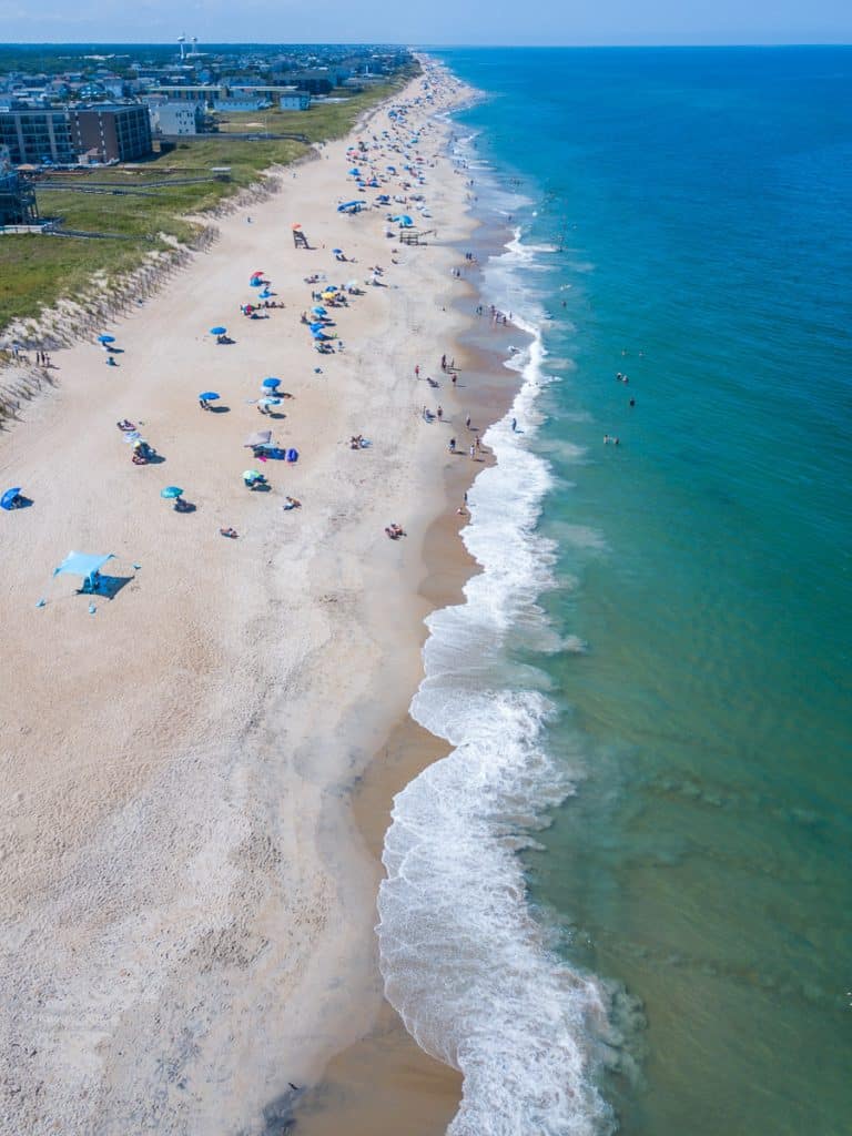 Aerial view of a beach with people swimming and relaxing on the sand..