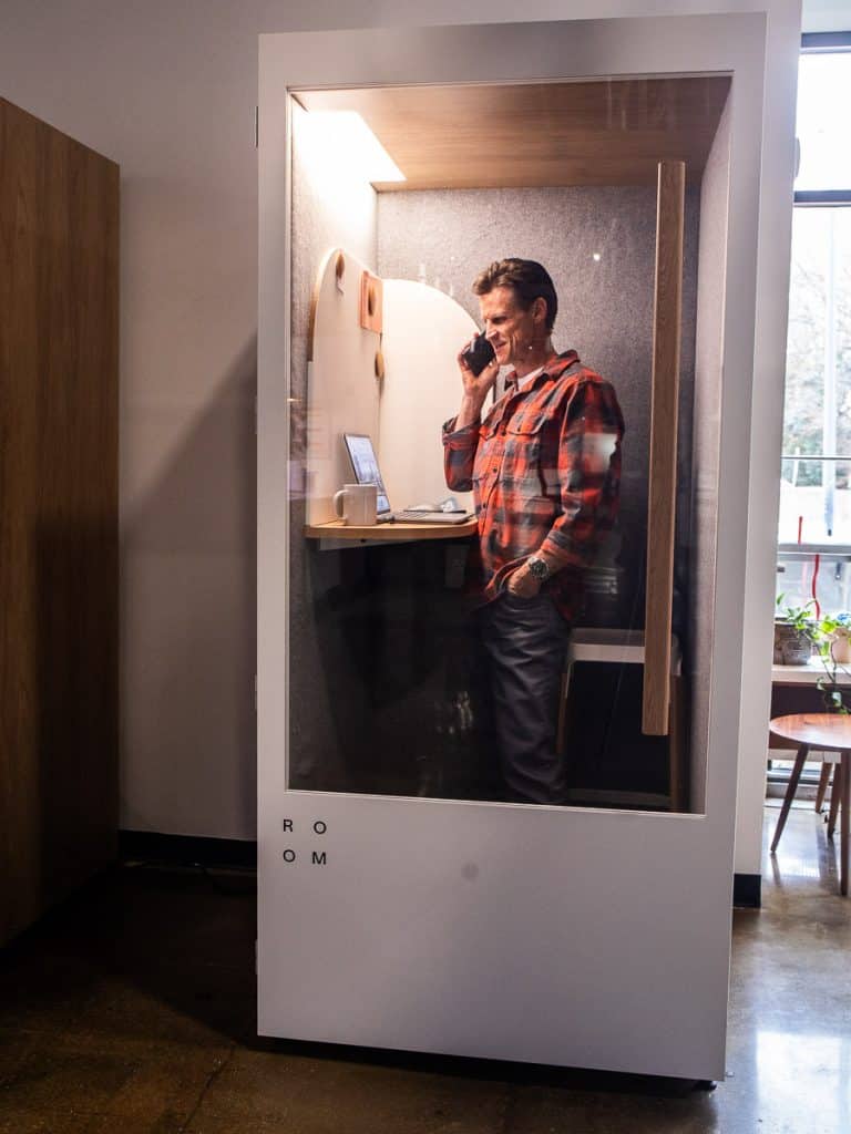Man standing in a booth on his phone.