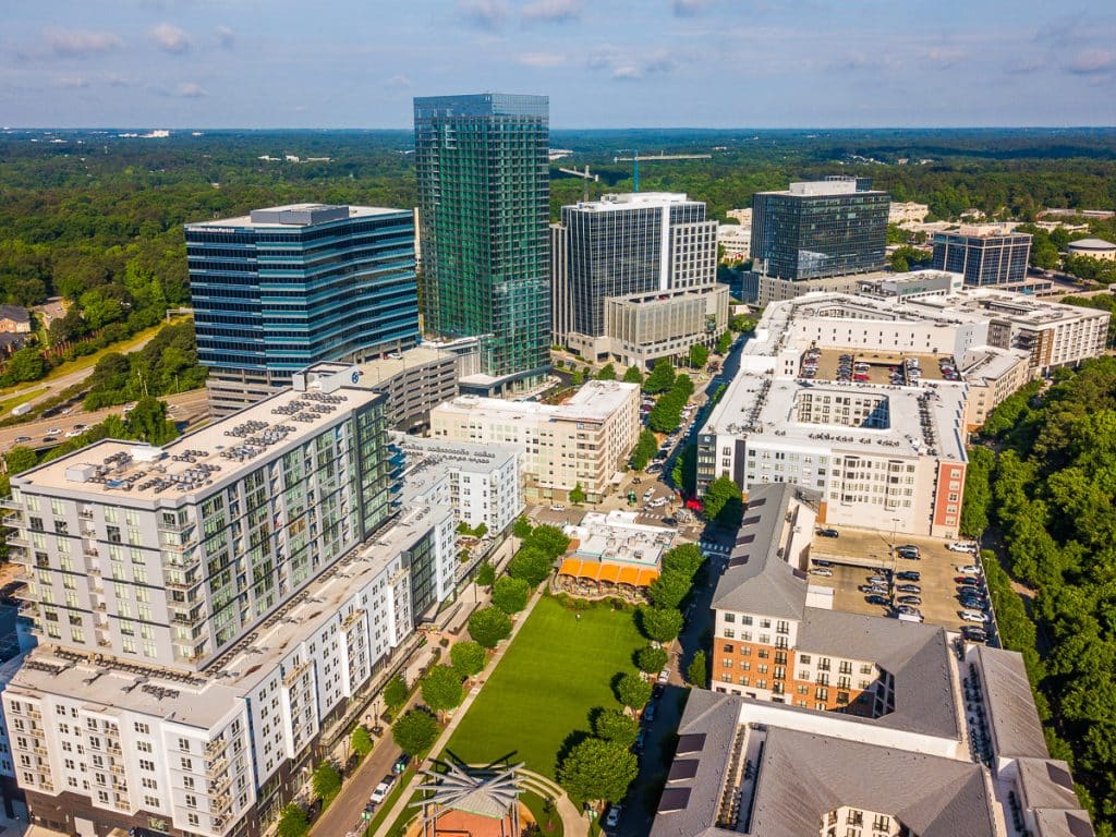 Aerial photo of a shopping district with high-rise buildings, parks, trees, and cars.