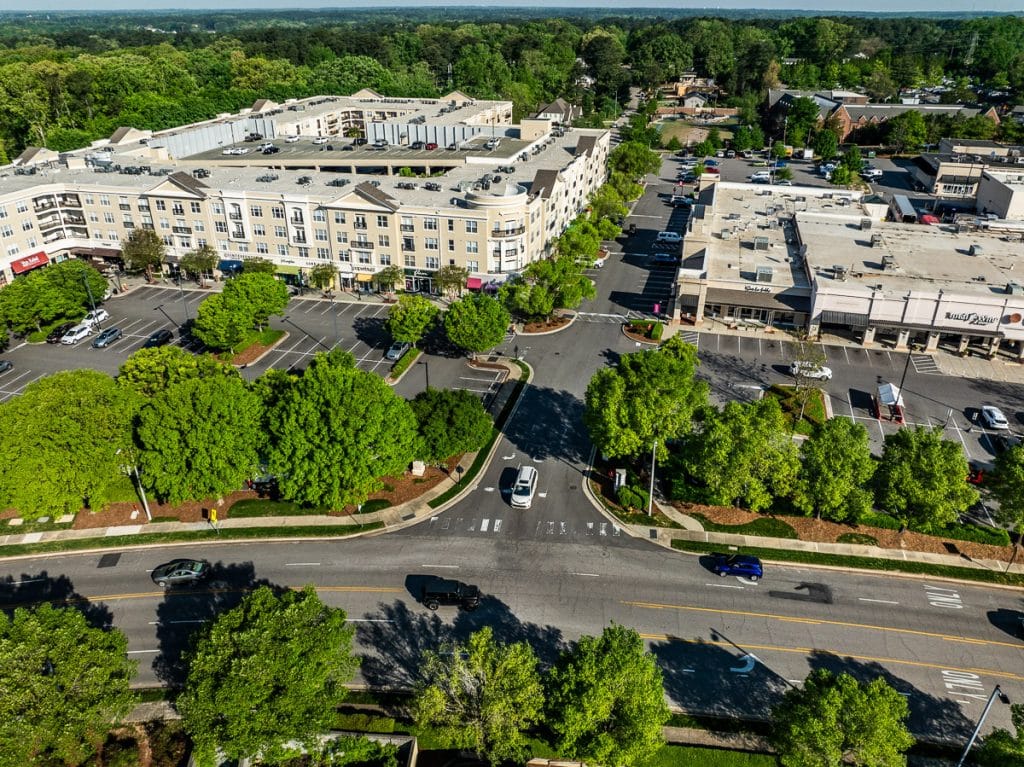 Outdoor shopping center called North Hills with buildings surrounded by trees and cars parked.