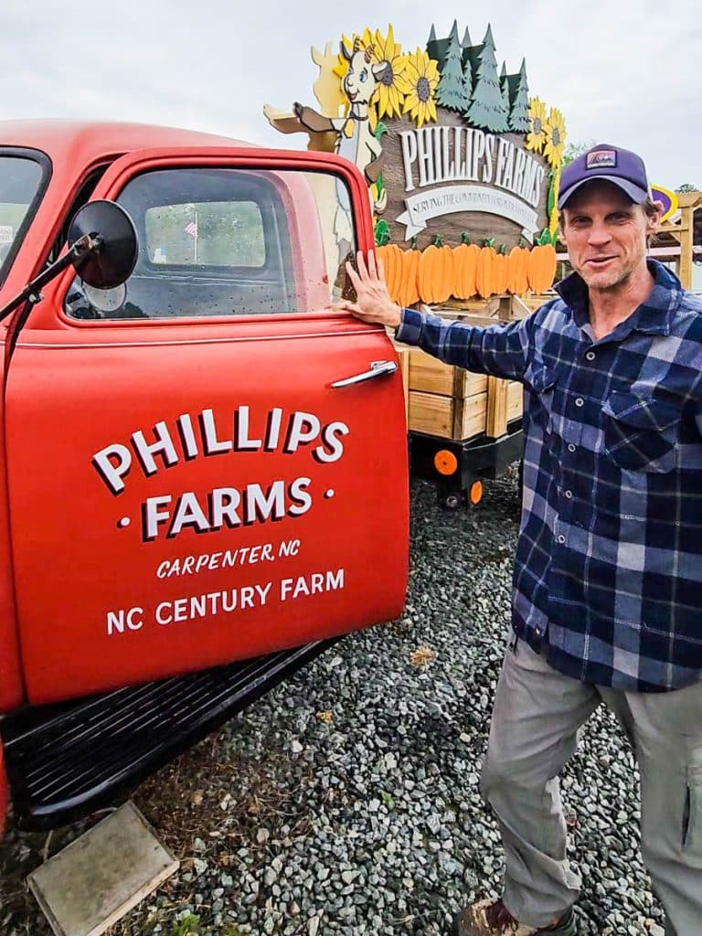man next to red truck with phillips farms written on it