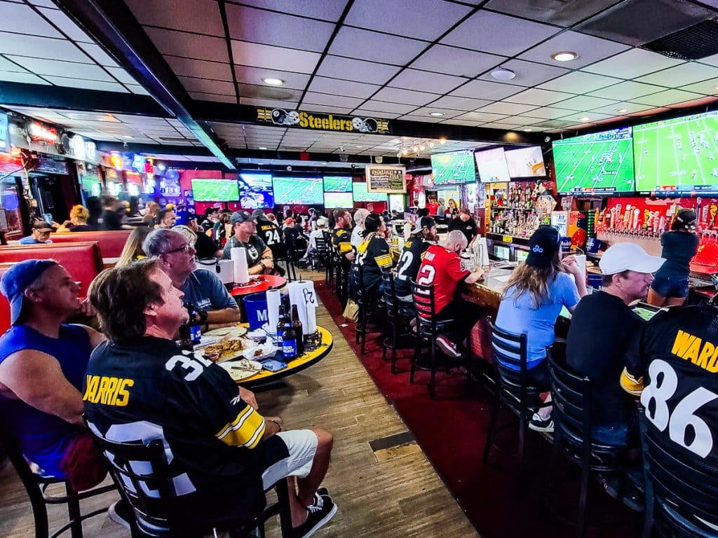 People in a sports bar watching sports on TVs and drinking beer.
