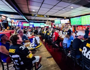 People in a sports bar watching sports on TVs and drinking beer.