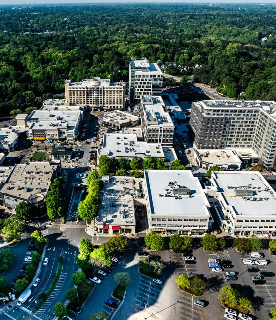 Outdoor shopping center called North Hills with buildings surrounded by trees and cars parked.
