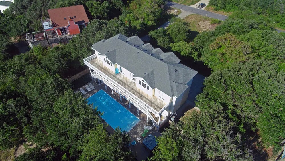 beach rental with pool surrounded by trees aerial view