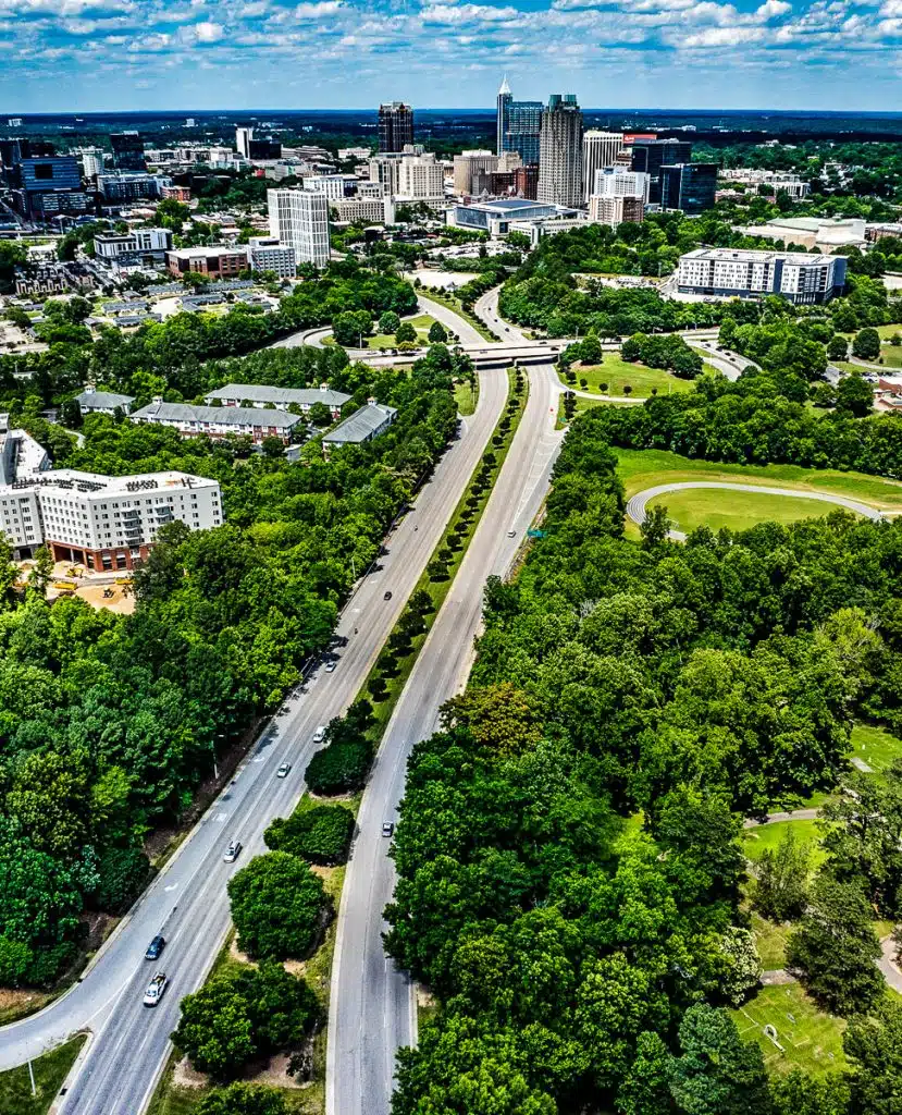 Aerial view of a road leading into the downtown skyline of the city of Raleigh.