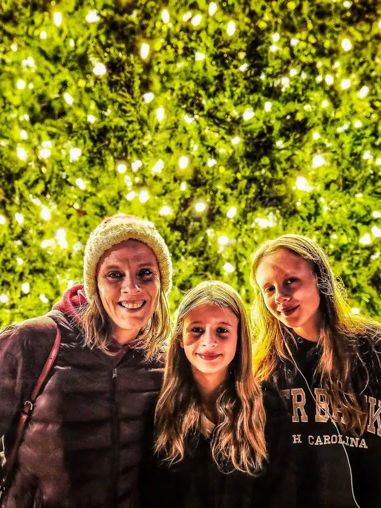 woman and two girls in front of christmas tree