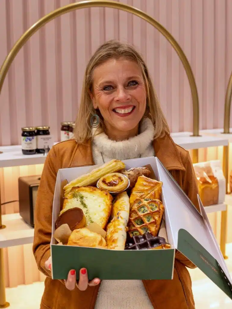 woman holding box of pastries from tous les jours
