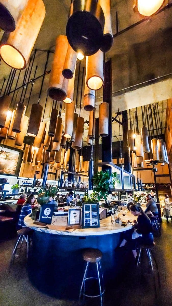 A wine bar with people sitting at the bar and lights hanging down.