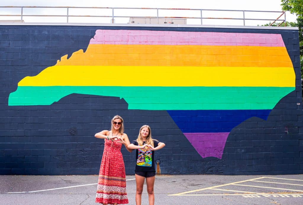 mother and child standing in front of nc rainbow flag