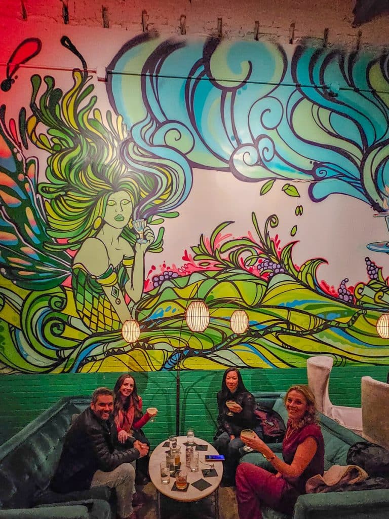 group of friends in front of mural at aunty betty's absinthe and gin bar