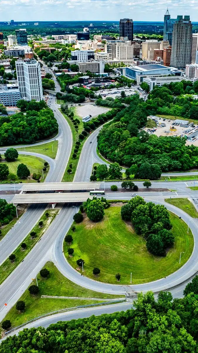 Aerial view of a road leading into the downtown skyline of the city of Raleigh.