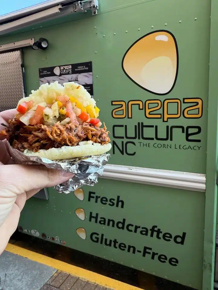 person holding arepa in front of arepa culture food truck