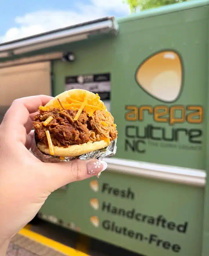 person holding arepa in front of arepa culture food truck