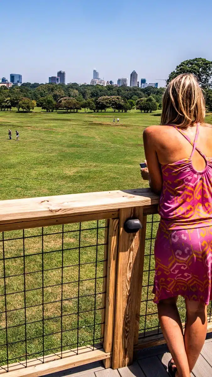 Lady standing at a fence overlooking a park