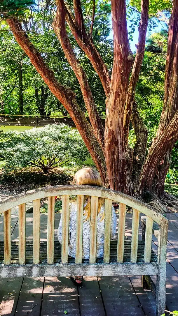 Girl sitting on a wooden seat in a garden
