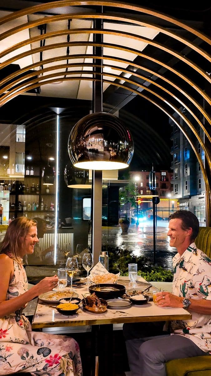 Man and woman having dinner in a restaurant with a gold arch over them.
