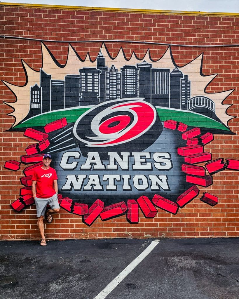 man standing in front of carolina hurricanes mural in raleigh