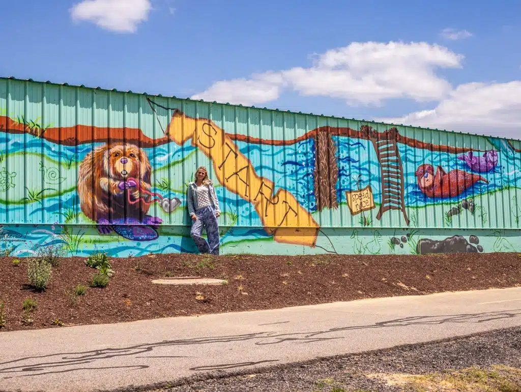 woman in front of otter mural on the river walk