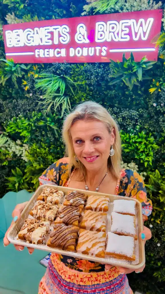 woman holding tray of beignets