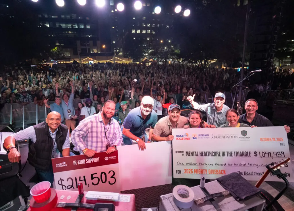 people on stage at mighty giveback concert holding check