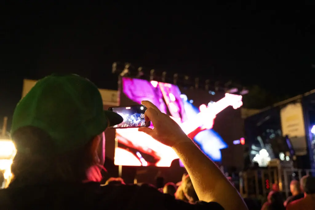 person takin photo of concert on phone at band together mighty giveback